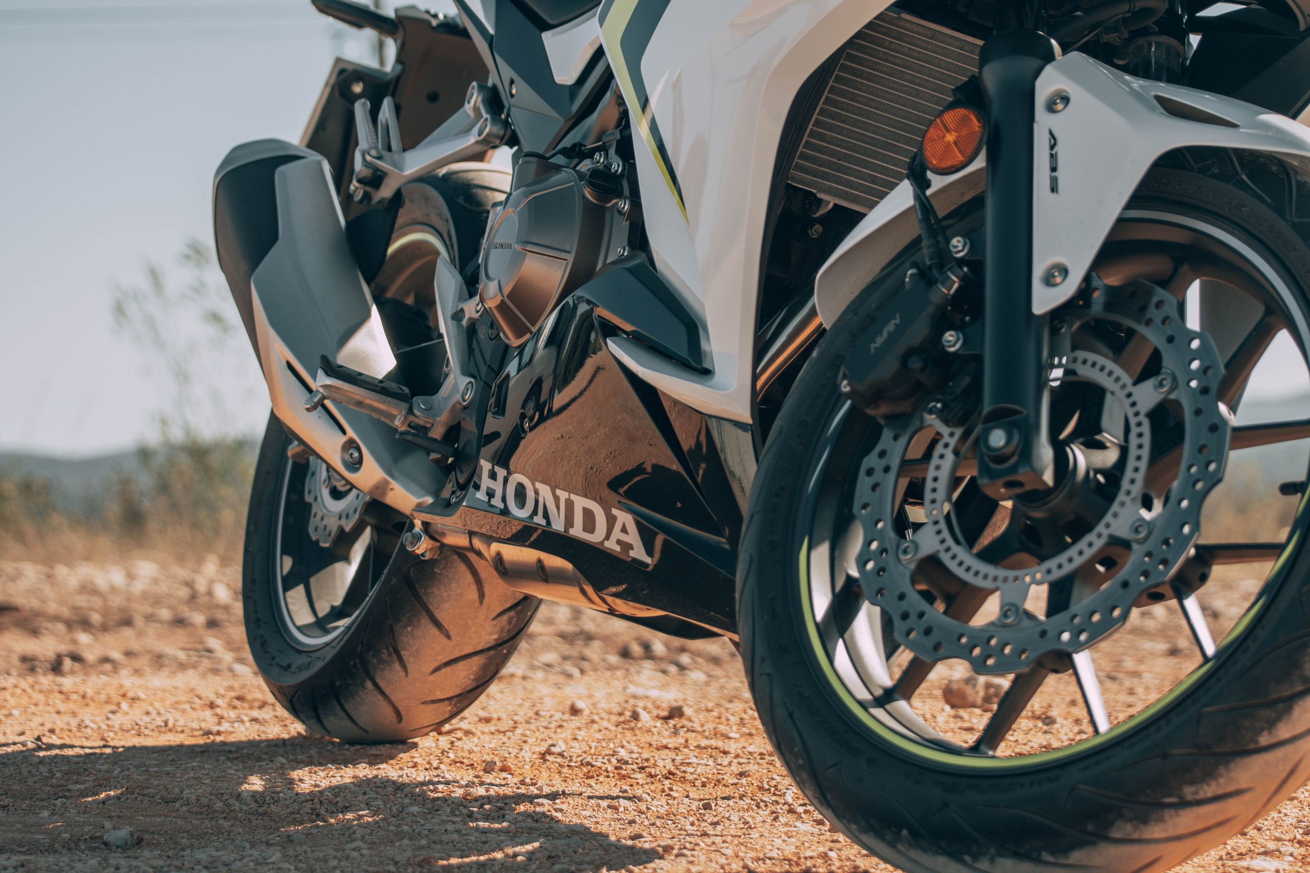 Detailed view of a Honda motorcycle's wheel and exhaust outdoors.