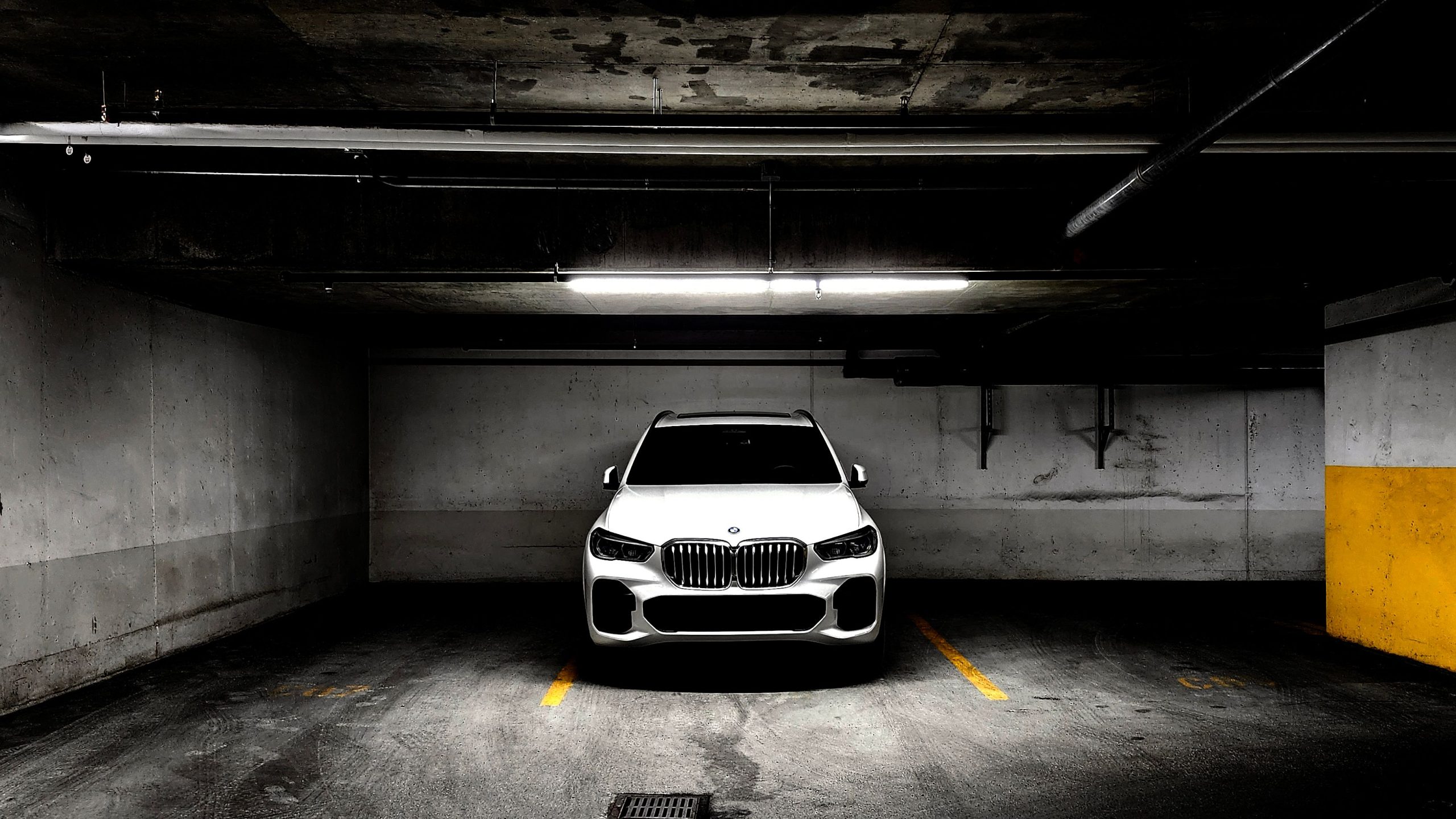 A sleek white BMW parked in a dimly lit underground garage, highlighting modern car design.