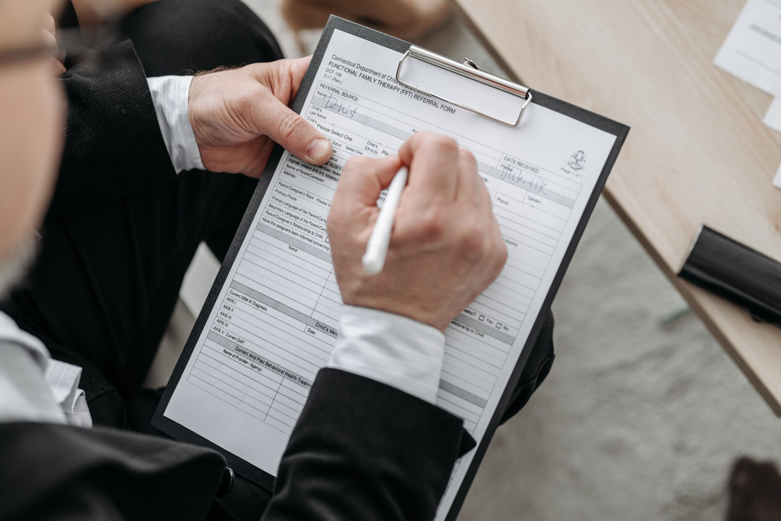 Close-up of a businessman signing a formal document on a clipboard.